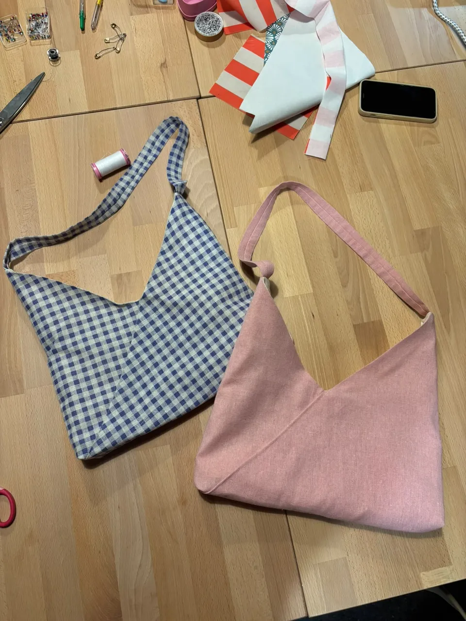 Hotová kostkovaná a růžová kabelka vedle šicího stroje po workshopu